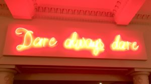 A photo of neon sign saying 'Dare always dare' in The Old Vic theatre in london