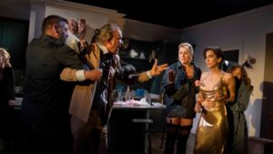 An aggressive man is held back in a confrontation with a trans woman in a scene from the play The Sex Party