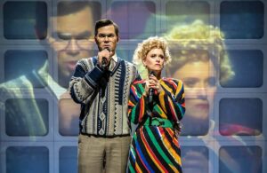 Actors Andrew Rannells and Katie Brayben stand together singing a song in a scene from Tammy Faye the musical at the Almeida Theatre