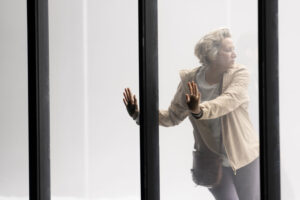 Production shot from Phaedra at the National Theatre in February 2023 showing Janet McTeer leaning against a glass wall