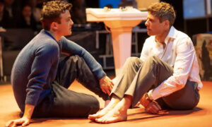 Luke Thompson and James Norton, two actors in A Little Life, are seated on the ground looking at each other