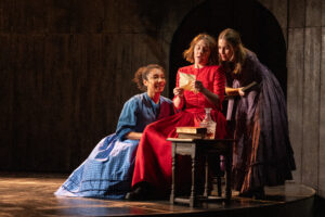 Three actors Adele James, Gemma Whelan and Rhiannon Clements gather round to read a letter in a scene from Underdog: The Othe Other Bronte at the National Theatre