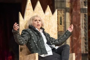 Actor Michelle Terry playing Richard III sits on a throne