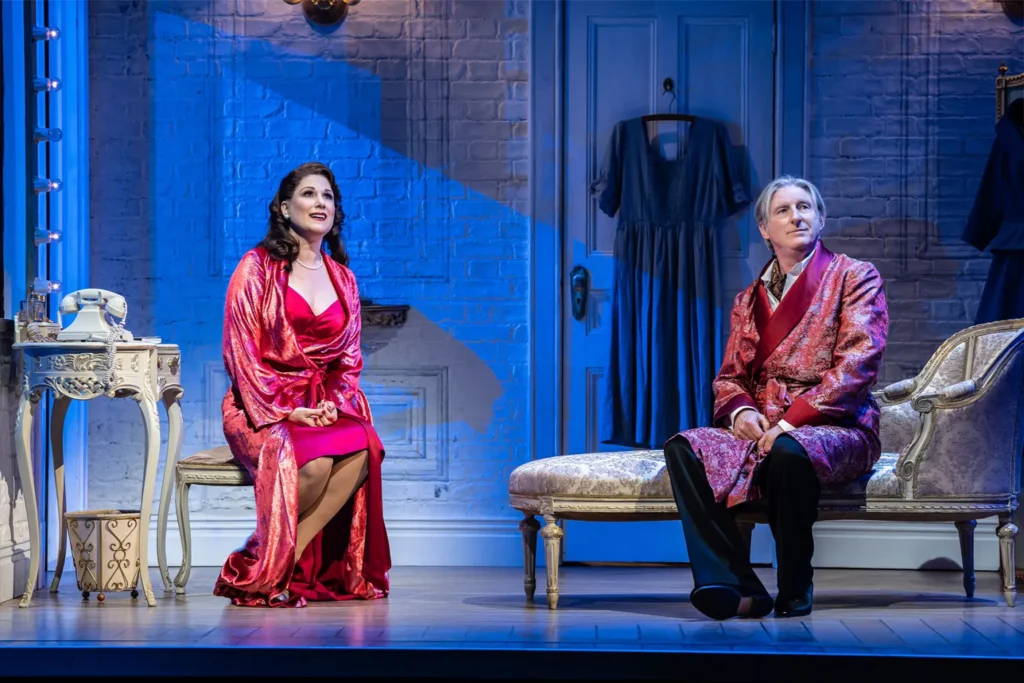 Stephanie J Block and Adrian Dunbar sit in dressing gowns in a theatre dressing room in a scene from Kiss Me Kate at the Barbican Theatre London 