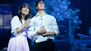 A young female and male couple stand close together looking out in a scene from the stage musical Your Lie in April at the Harold Pinter Theatre