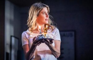 A woman carries a birthday cake in a scene from Next To Normal at Wyndham's Theatre in London