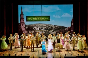 A chorus line dance in front of a backdrop of Yonker New York in the nineteenth century as part of the London Palladium production of Hello, Dolly! August 2024