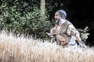 Actor Adam Dannheisser walks through wheat field in a scene from Fiddler on The Roof at the Open Aitr Theatre